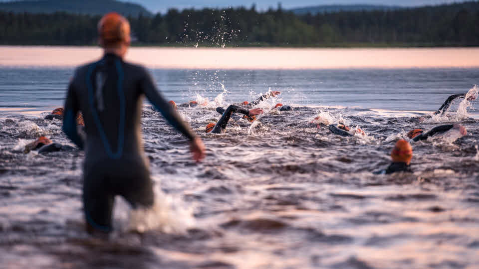 Flera simmare med våtdräkt i en sjö
